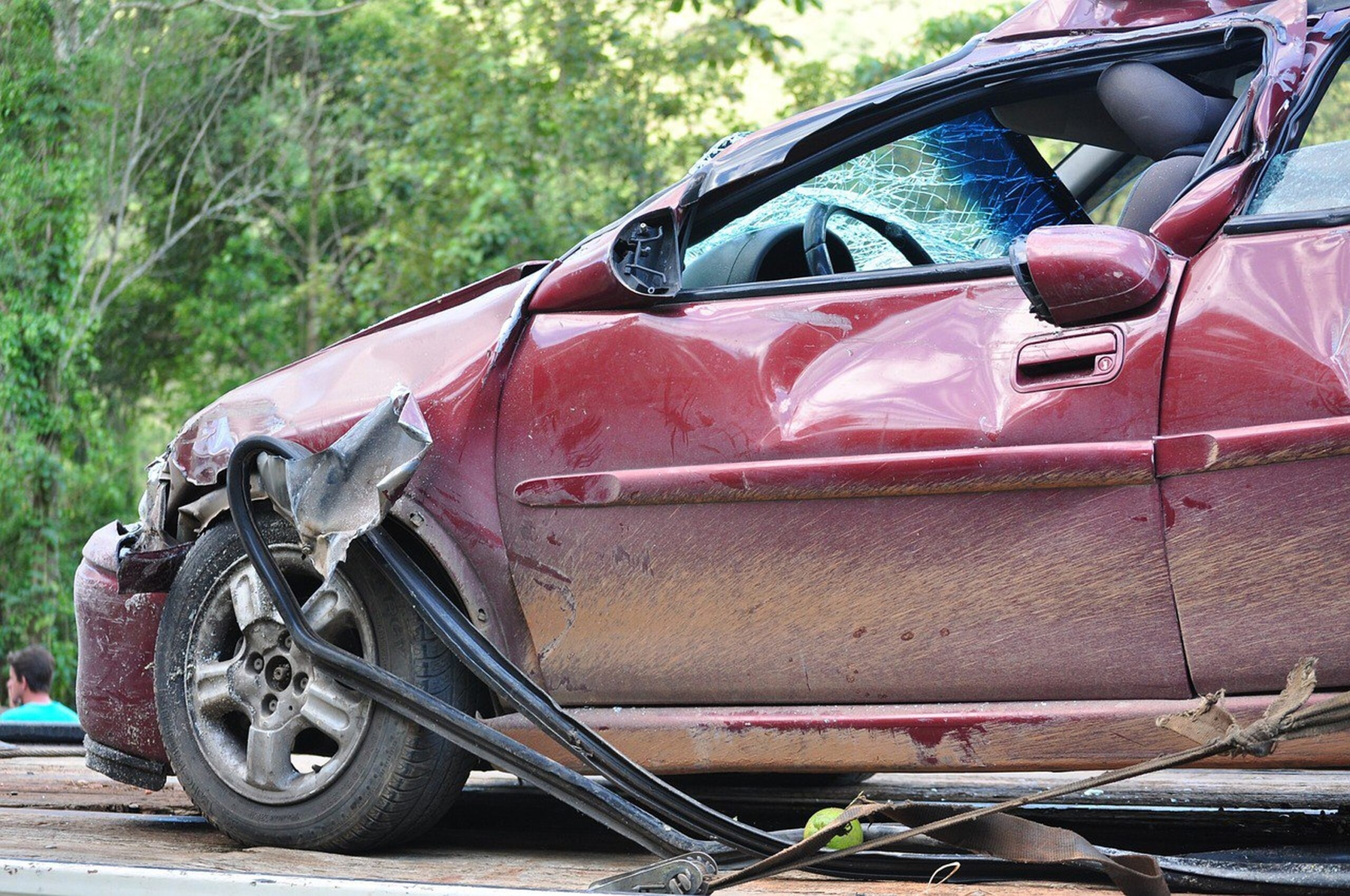 Severely damaged red car with broken windshield.